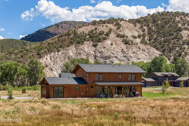 a view of a house with a big yard and large tree