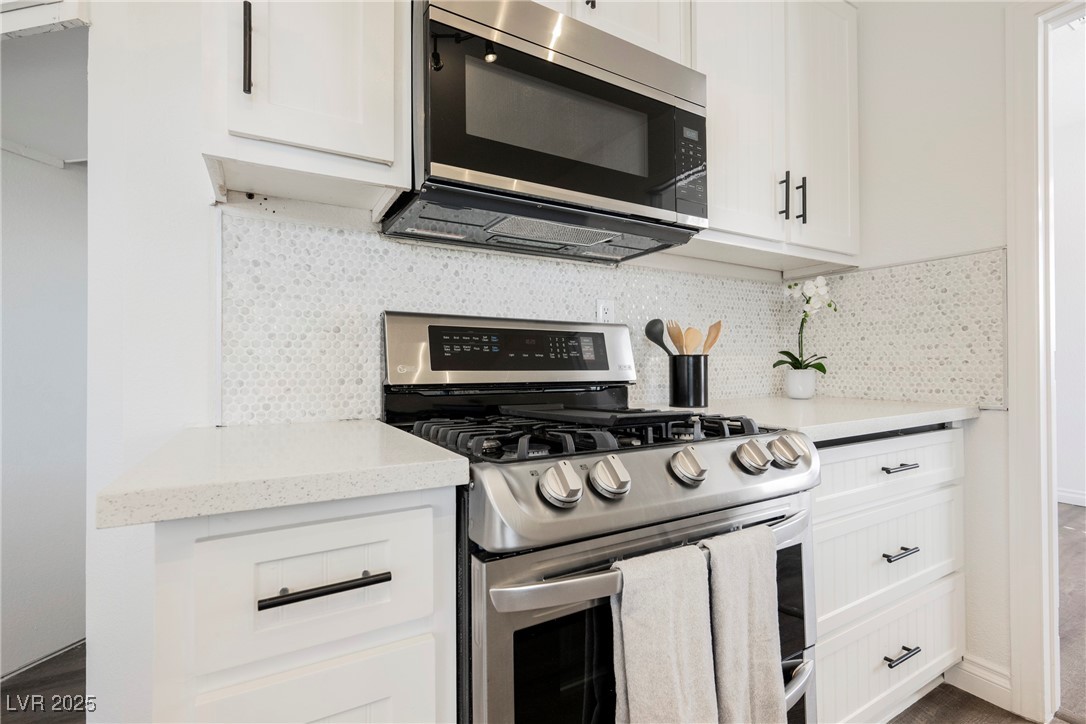 1706 Toltec Circle Henderson, NV 89014 - Photo 13 of 21 Kitchen with appliances with stainless steel finishes, light stone countertops, white cabinetry, and decorative backsplash