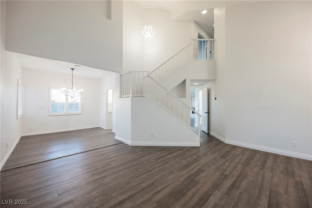 1706 Toltec Circle Henderson, NV 89014 - Photo 10 of 21 Unfurnished living room with a chandelier, a high ceiling, dark wood-style floors, and stairway
