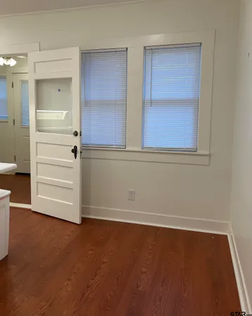 an empty room with wooden floor closet and windows