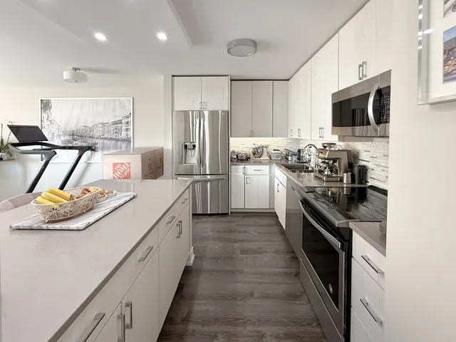 a kitchen with stainless steel appliances kitchen island granite countertop a refrigerator and a stove top oven