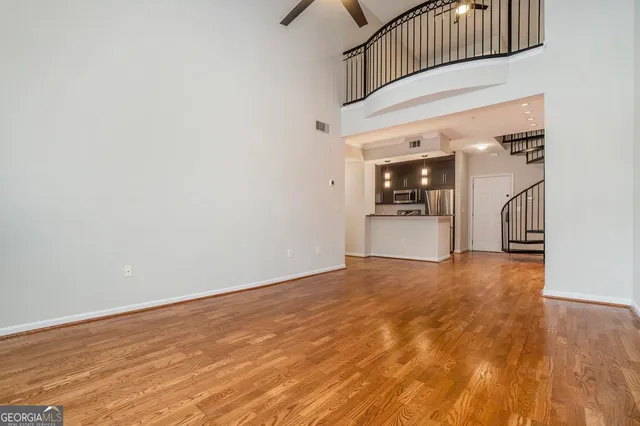 an empty room with wooden floor and a kitchen