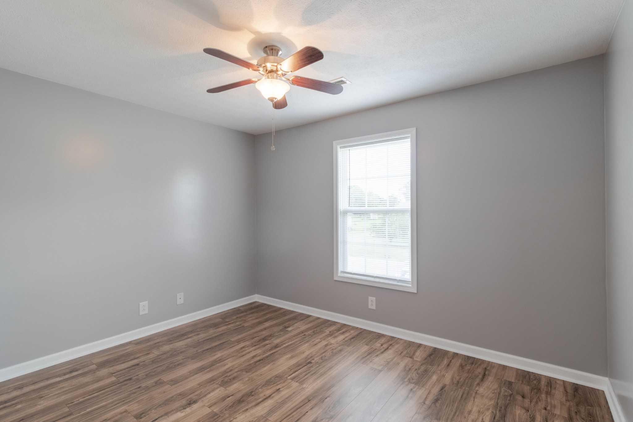 11241 Bell Station Road Oak Grove, KY 42262 - Photo 23 of 33 an empty room with wooden floor chandelier fan and windows