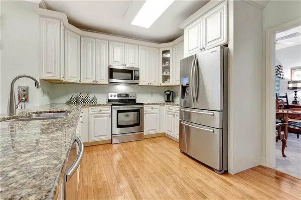 a kitchen with granite countertop a refrigerator sink and white cabinets