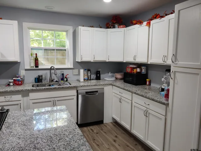a kitchen with white cabinets and window