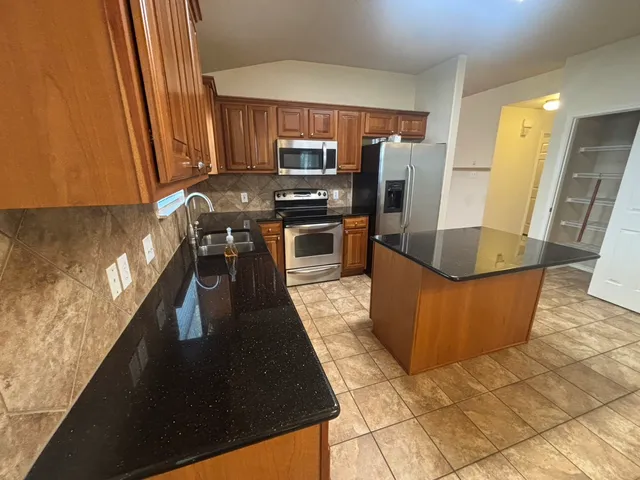 a kitchen with stainless steel appliances granite countertop a stove a sink a microwave and a refrigerator