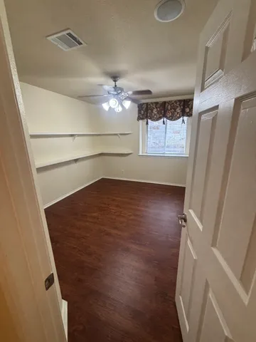 en empty room with wooden floor and fan