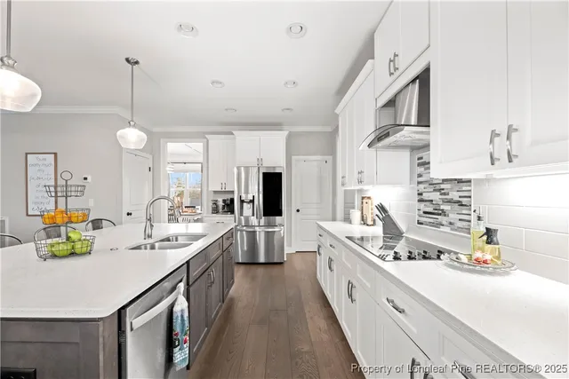 a large white kitchen with kitchen island a stove a sink a chimney and a dining table