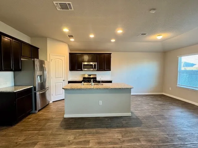 a large kitchen with stainless steel appliances wooden floors and wooden cabinets