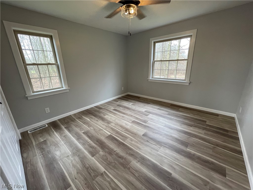 6135 California Road Williamsfield, OH 44093 - Photo 20 of 37 Unfurnished room with ceiling fan, a wealth of natural light, and wood-type flooring