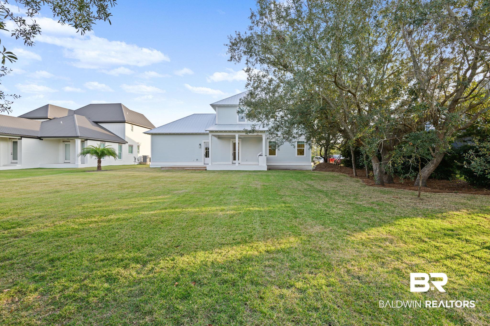 30313 River Road Orange Beach, AL 36561 - Photo 10 of 50 Rear view of house featuring a yard, a patio area, and a metal roof