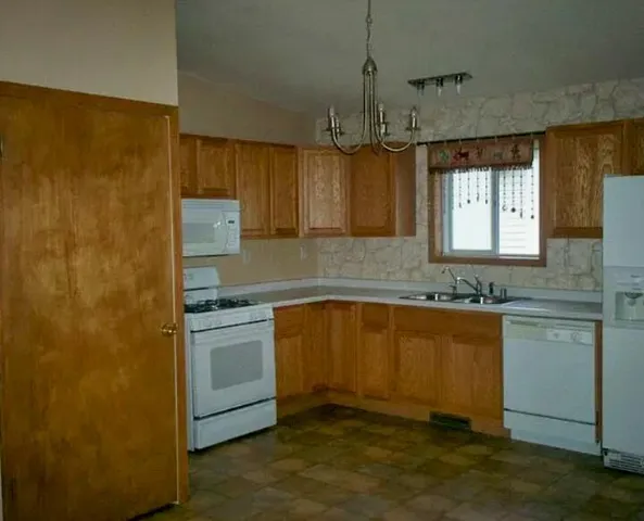 a kitchen with stainless steel appliances granite countertop a sink a stove a refrigerator a microwave oven with white cabinets