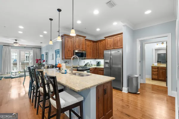 a kitchen with stainless steel appliances granite countertop a refrigerator a sink dishwasher a stove with wooden floor and cabinets