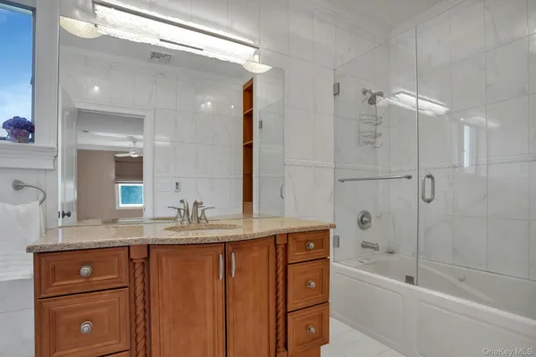 a bathroom with a granite countertop sink a mirror a bathtub and shower