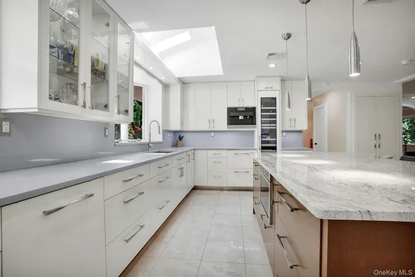 a large kitchen with granite countertop a sink and white cabinets