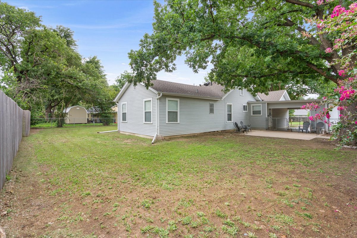1607 North Harding Avenue Cameron, TX 76520 - Photo 35 of 37 A spacious backyard features a concrete patio, mature trees, and a convenient storage shed.