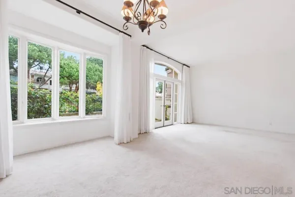 a view of a big room with windows and chandelier fan