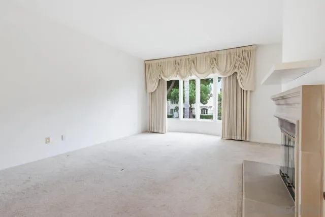 a view of an empty room with a fireplace and a window