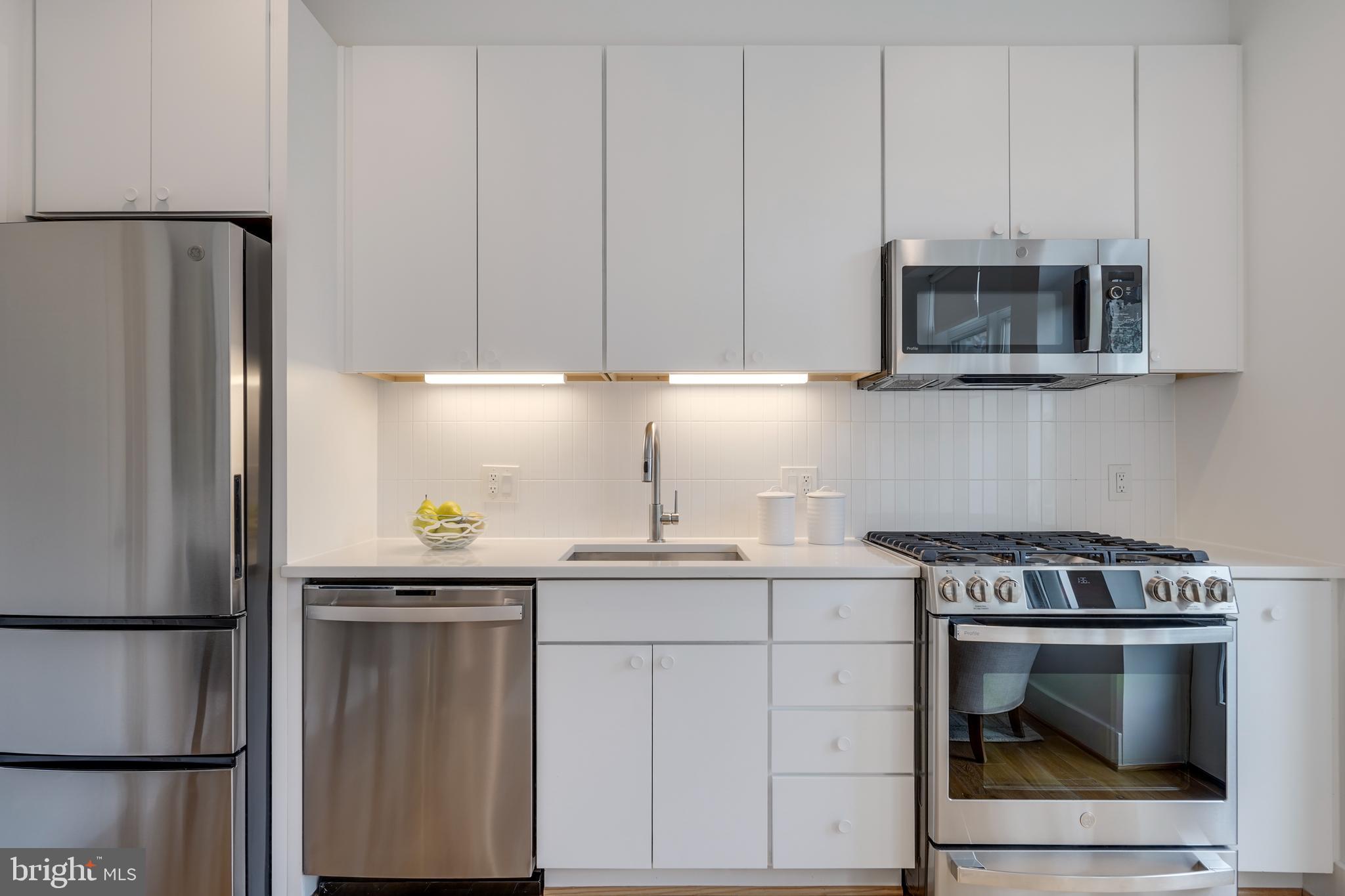 2419 Ontario Road Northwest, Unit 202 Washington, DC 20009 - Photo 6 of 15 a kitchen with stainless steel appliances a stove a microwave and a refrigerator