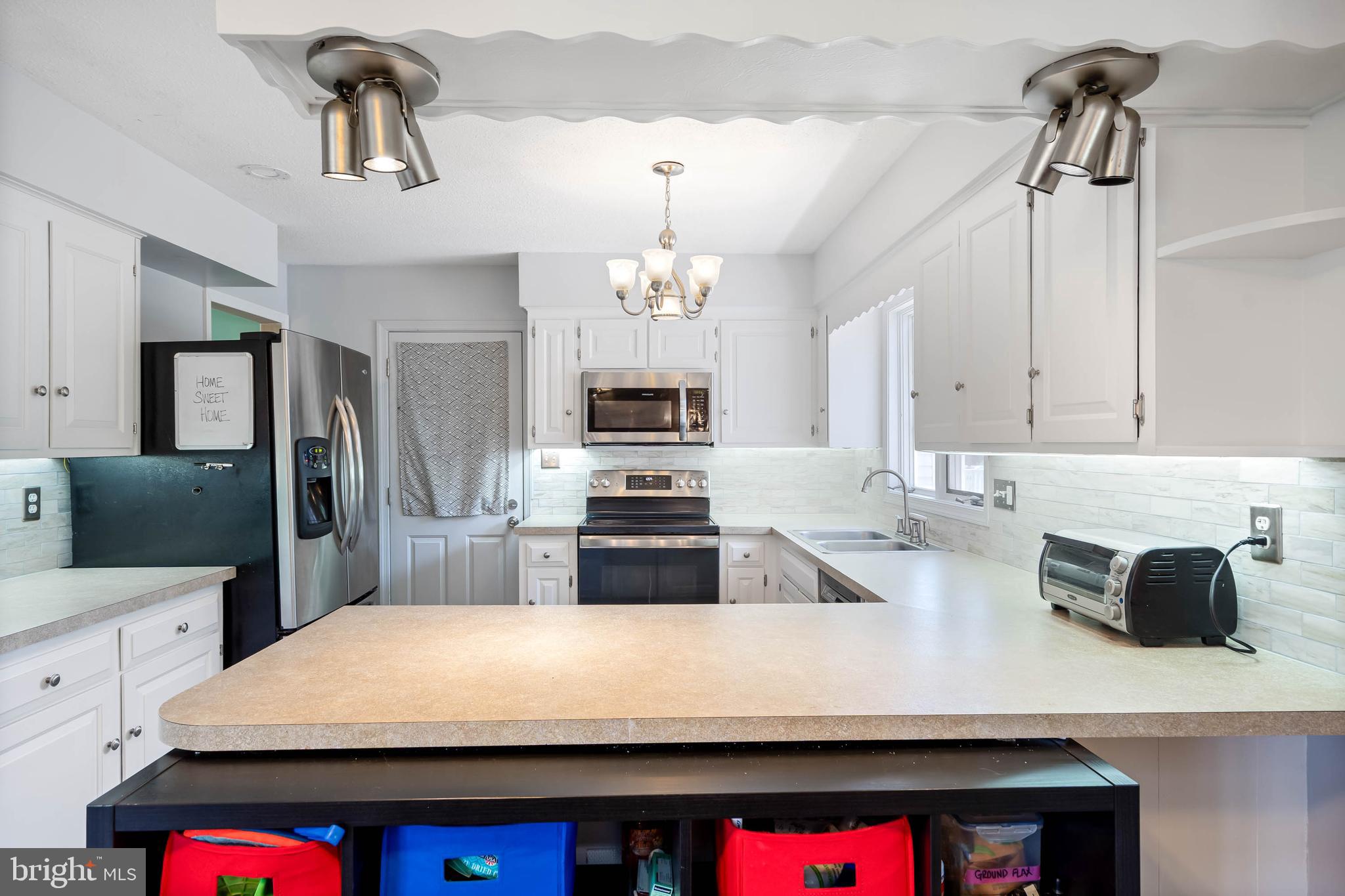 521 Harbor Road Ocean View, DE 19970 - Photo 3 of 46 a large kitchen with sink a refrigerator and chandelier