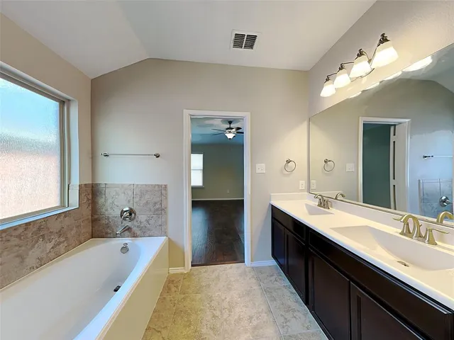 a spacious bathroom with a tub double sink mirror and