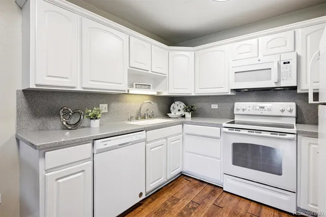 a kitchen with granite countertop white cabinets and white appliances