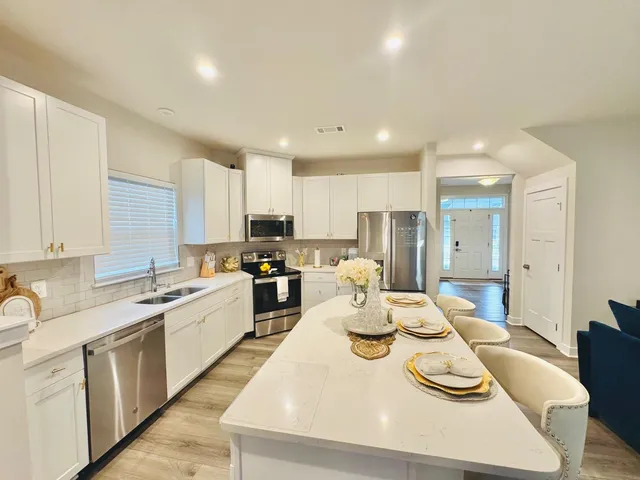 a open dining room with stainless steel appliances kitchen island granite countertop a sink a stove a dining table and chairs