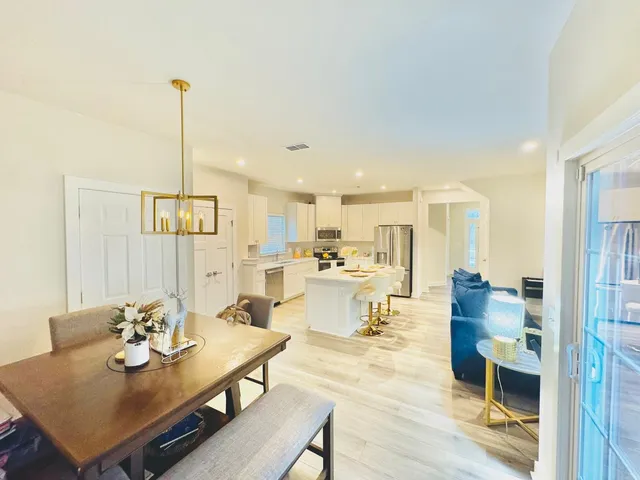 a view of a dining room and livingroom with furniture wooden floor a rug and a chandelier