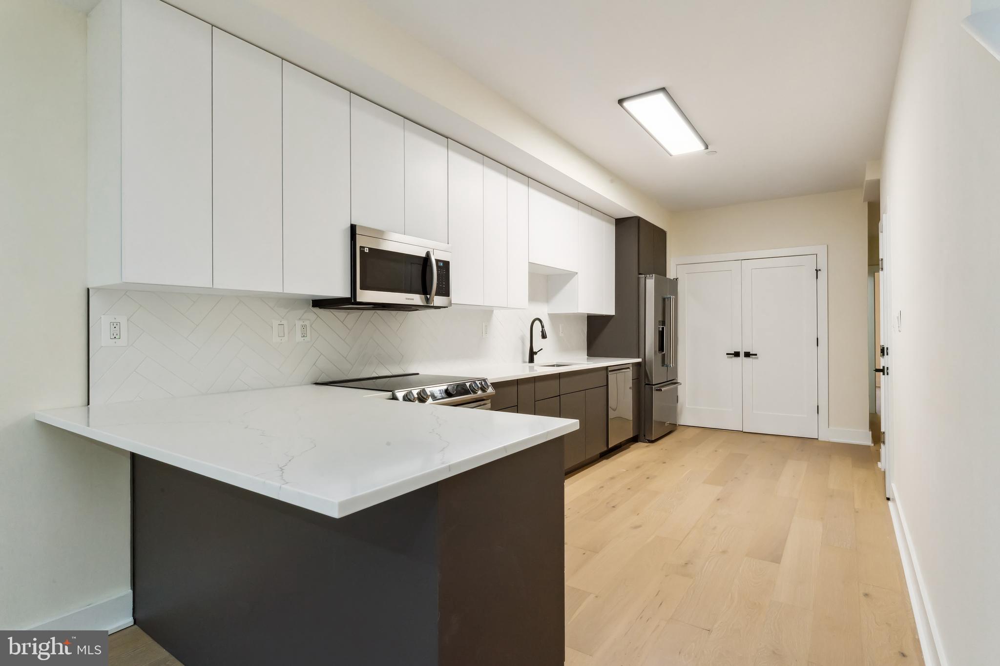329 16th Street Southeast Washington, DC 20003 - Photo 11 of 39 a kitchen with a stove a refrigerator a sink a microwave oven and white cabinets with wooden floor