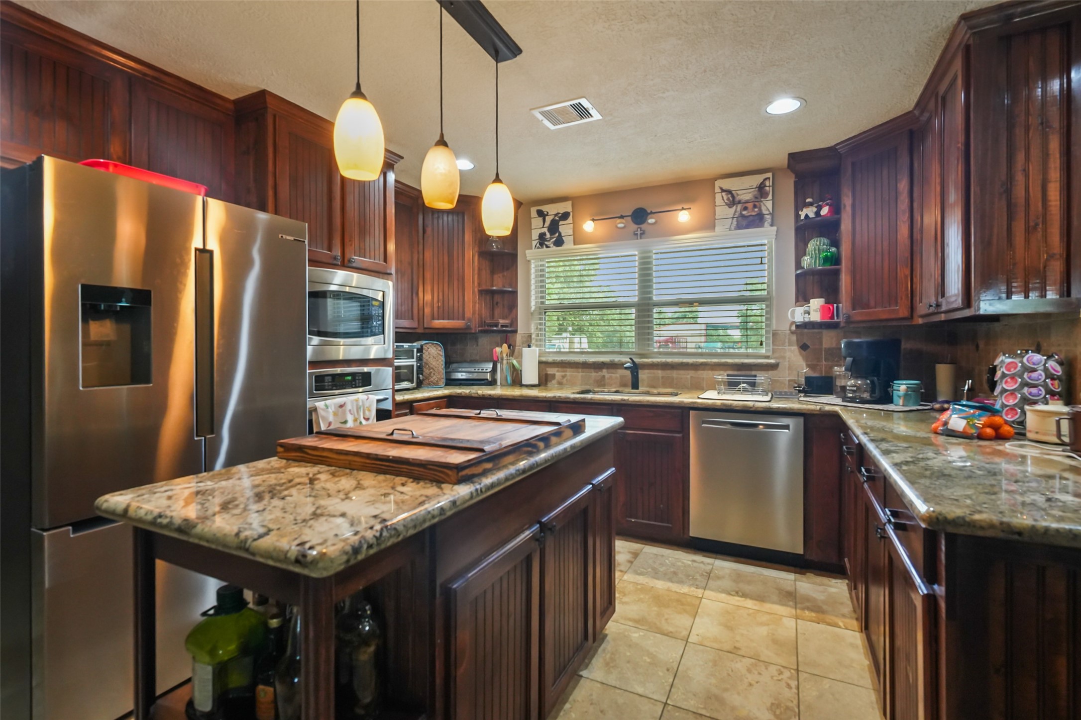 34366 Owens Road Hempstead, TX 77445 - Photo 11 of 46 Spacious kitchen featuring granite countertops, rich wood cabinetry, stainless steel appliances, a center island with seating, and plenty of prep space, all overlooking the backyard through a large picture window.