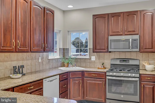 a kitchen with stainless steel appliances granite countertop wooden cabinets a stove and a sink