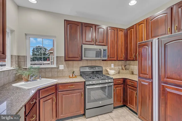 a kitchen with stainless steel appliances granite countertop a stove a sink dishwasher and wooden cabinets