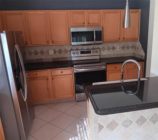 a kitchen with granite countertop a stove a microwave a sink and cabinets