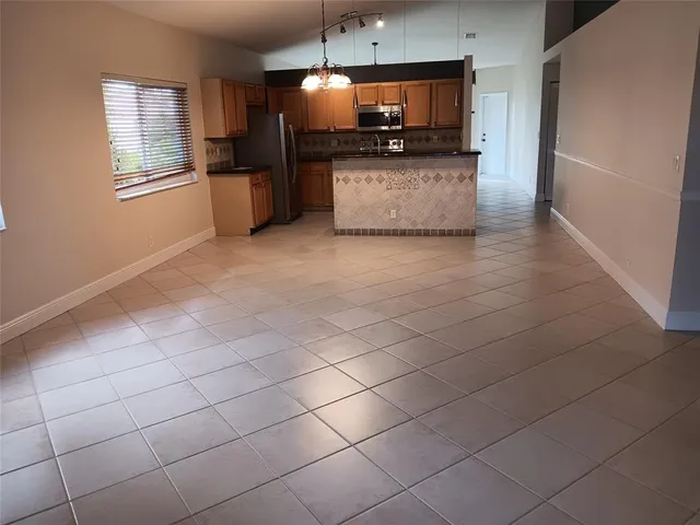 a kitchen with stainless steel appliances kitchen island granite countertop a sink a stove top oven a counter space and cabinets