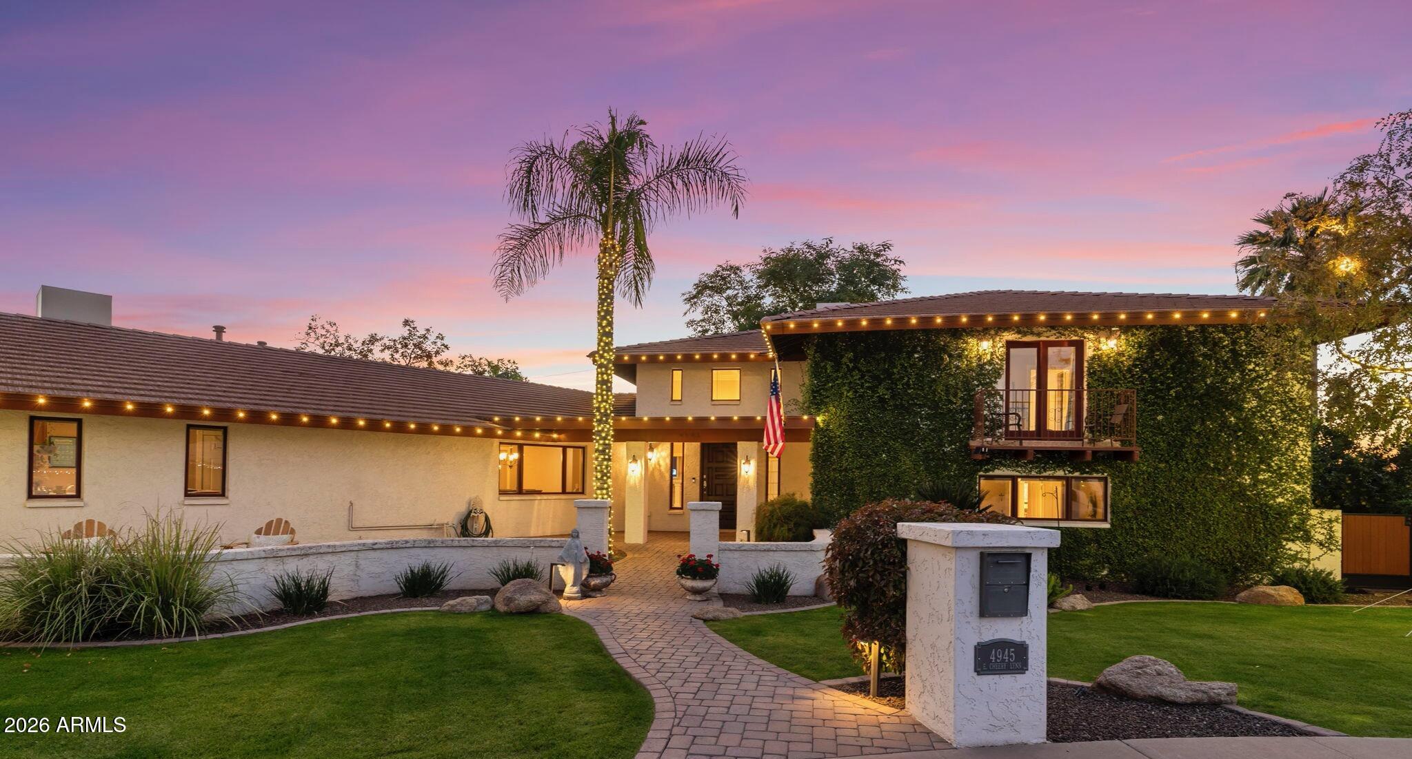 a front view of a house with a garden and a tree