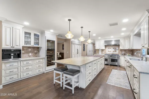 a large kitchen with granite countertop lots of white cabinets appliances and a chandelier