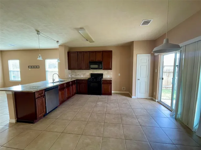 a large kitchen with granite countertop a stove a sink dishwasher and a refrigerator