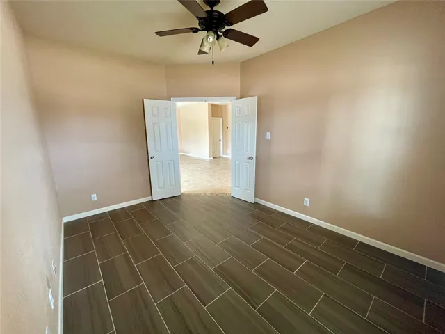 an empty room with a ceiling fan and carpet