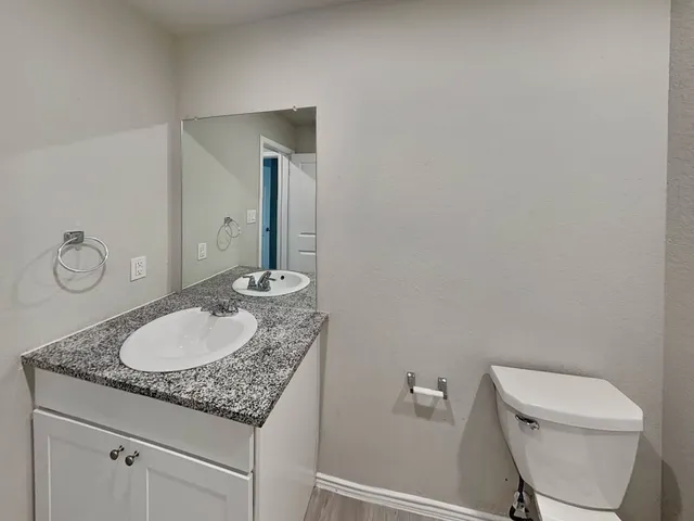a bathroom with a granite countertop sink toilet and mirror
