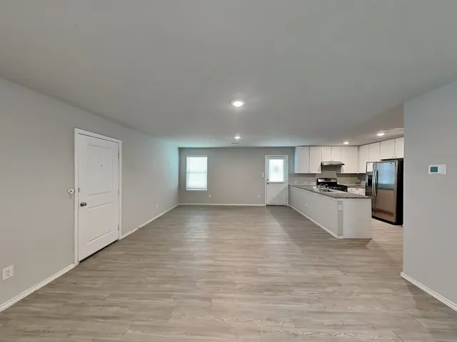 a view of a kitchen with kitchen island a sink wooden floor and stainless steel appliances
