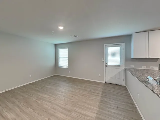 a view of an empty room with a window and wooden floor