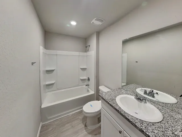a bathroom with a granite countertop sink toilet a bathtub and a shower