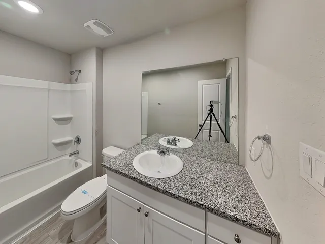 a bathroom with a granite countertop sink toilet and shower