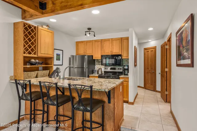 a kitchen with stainless steel appliances kitchen island granite countertop a refrigerator and cabinets