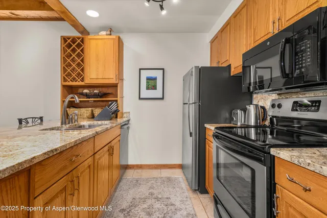 a kitchen with stainless steel appliances granite countertop a refrigerator a stove and a sink