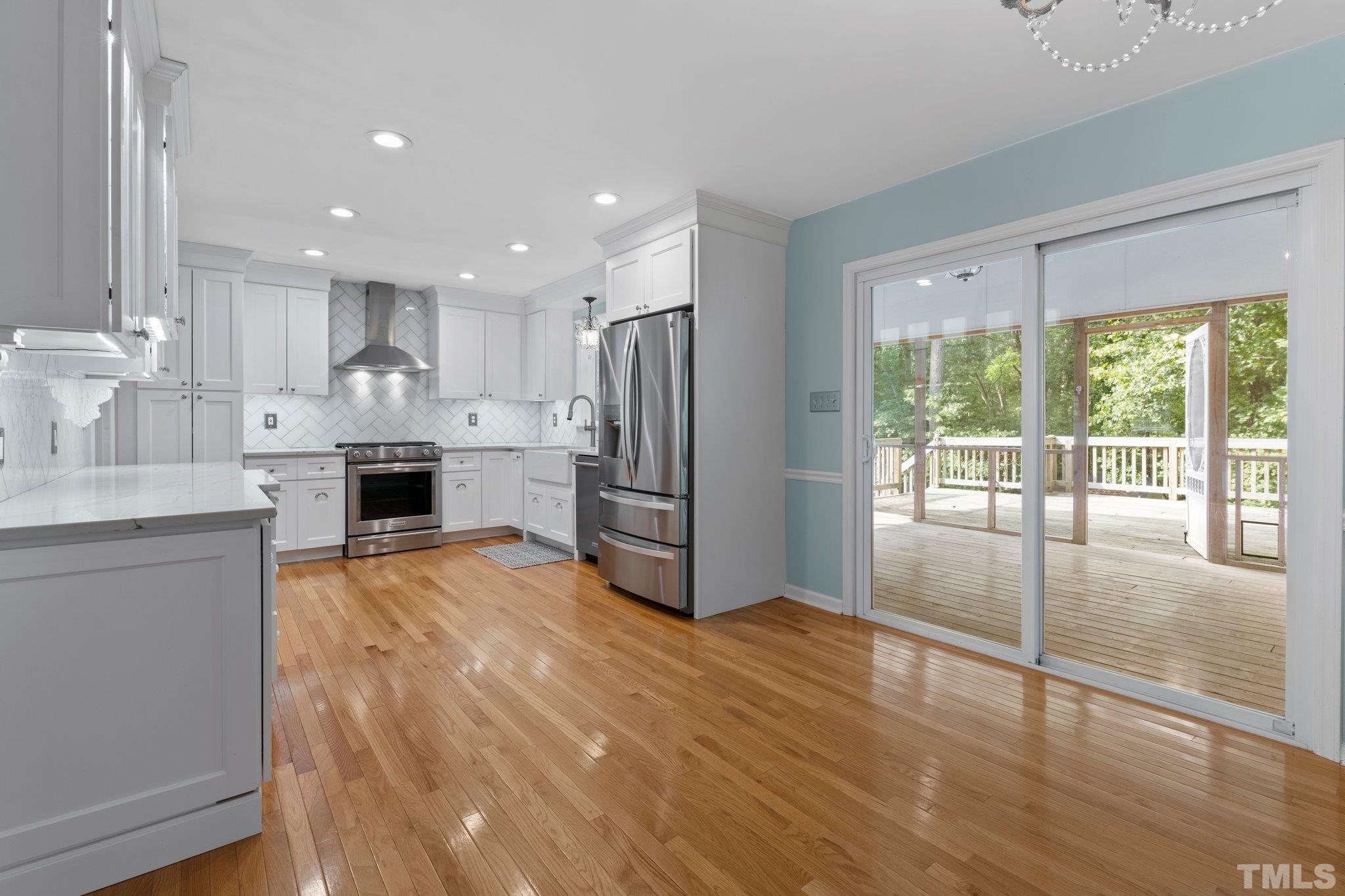 5101 Raintree Road Durham, NC 27712 - Photo 9 of 30 a open kitchen with stainless steel appliances kitchen island granite countertop a refrigerator stove oven and white cabinets with wooden floor