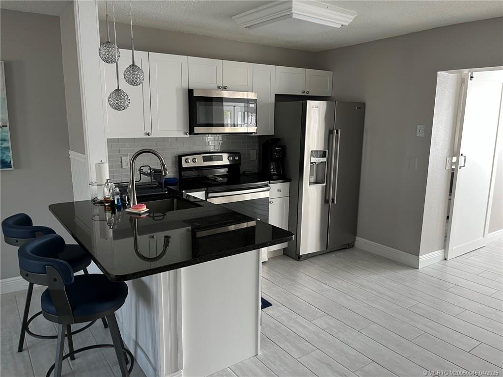 2340 Northeast Rustic Way Jensen Beach, FL 34957 - Photo 2 of 19 a kitchen with stainless steel appliances a sink a microwave a refrigerator and cabinets
