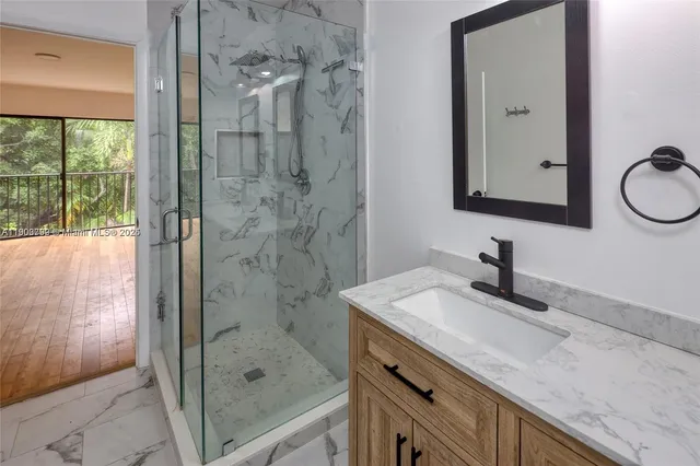 a bathroom with a granite countertop sink a mirror and shower