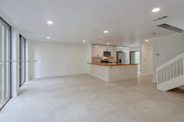a view of kitchen with kitchen island white cabinets and stainless steel appliances