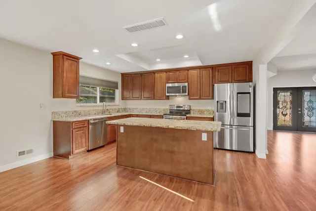 a open kitchen with kitchen island a sink appliances and a fireplace